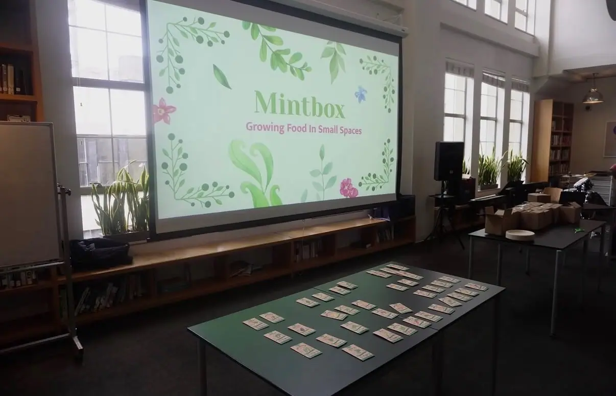The Growing Food in Small Spaces presentation on screen, with seed variety cards laid out on the table.
